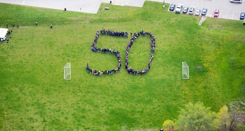 Photo take from the air of Centennial College staff on a soccer field, arranged to spell out a giant number 50